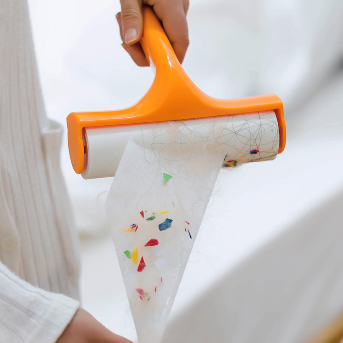 Manual lint roller hair remover removing visible lint and dust from a dark jacket.